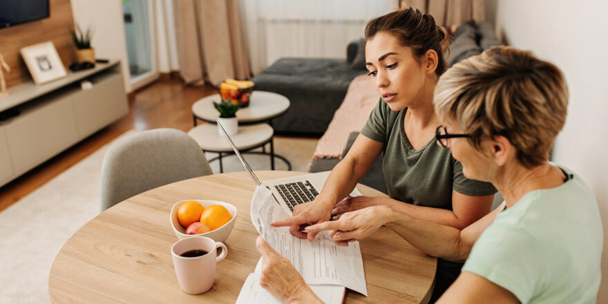 Mother and daughter discussing personal loan origination fee with a laptop