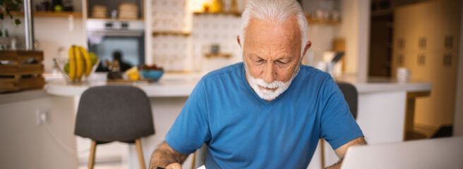 Older man looking at medical bills with a laptop