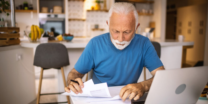 Older man looking at medical bills with a laptop