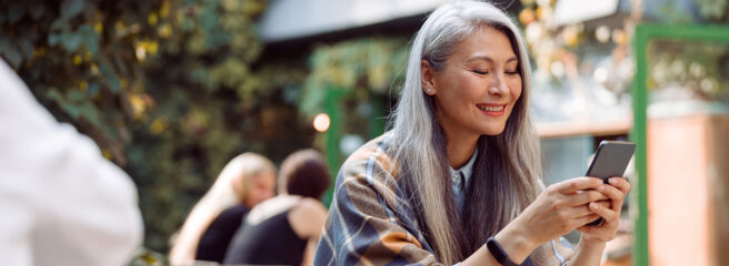 Older woman holding phone reading about borrowing from 401k