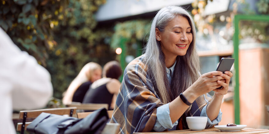 Older woman holding phone reading about borrowing from 401k