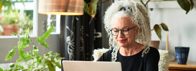 Grey haired older woman looking up credit-builder loan on laptop