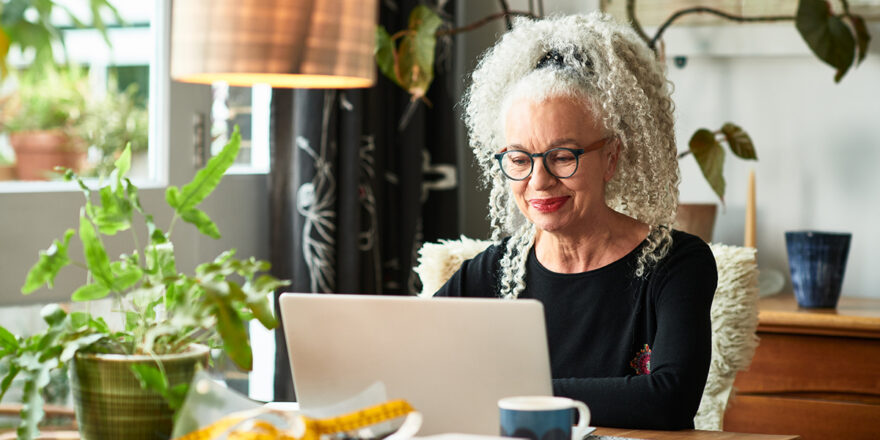 Grey haired older woman looking up credit-builder loan on laptop