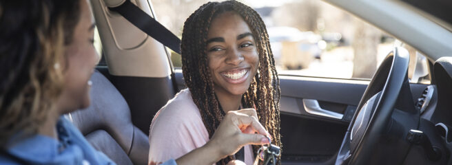 Young woman grabbing key from another person inside a car