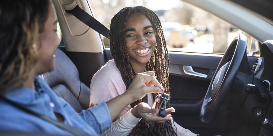 Young woman grabbing key from another person inside a car