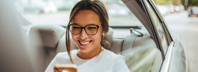 Woman in car backseat looking up lien on a car through a phone