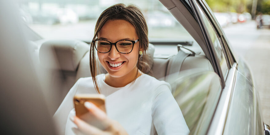 Woman in car backseat looking up lien on a car through a phone