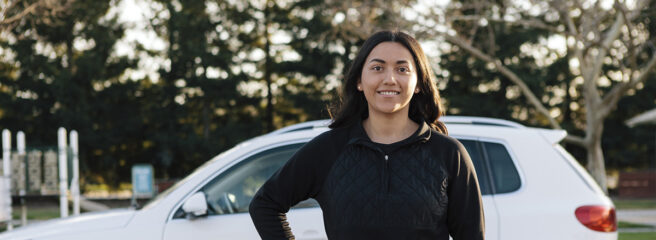 Women standing in front of white car after refinancing her car loan