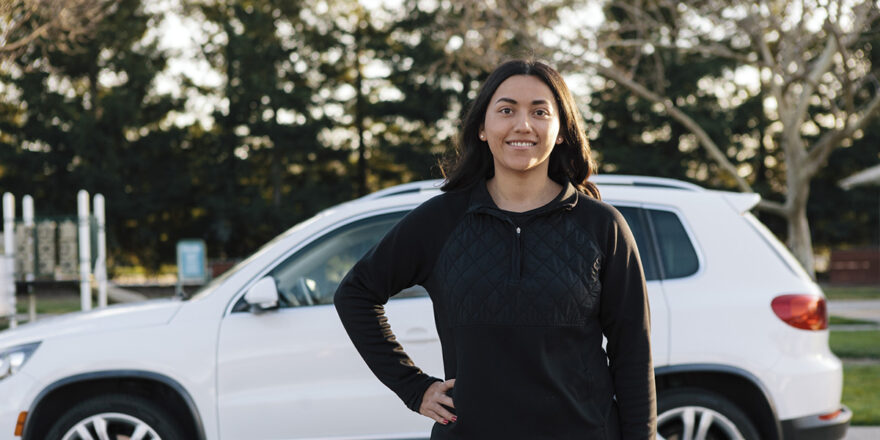 Women standing in front of white car after refinancing her car loan