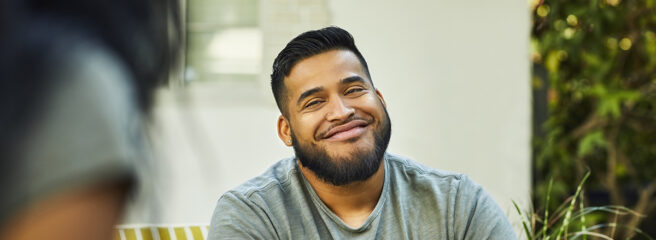Young man with beard smiling and feeling less stress after consolidating debt with a personal loan