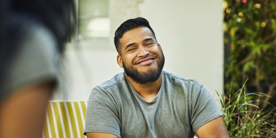 Young man with beard smiling and feeling less stress after consolidating debt with a personal loan