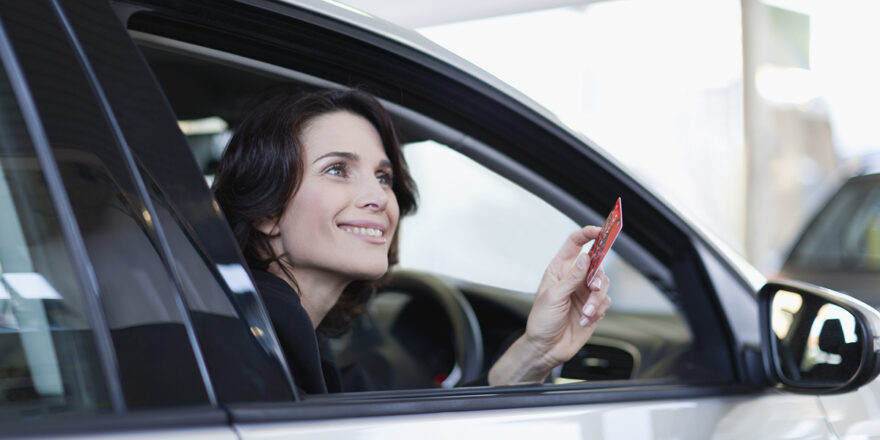 Woman in car holding a credit card to get medical payment coverag