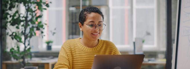 Young woman in a yellow sweater on a laptop researching the 4% retirement spending rule