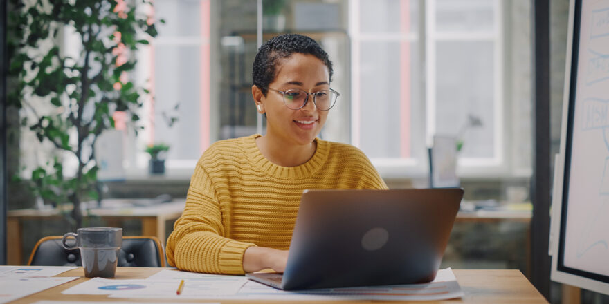 Young woman in a yellow sweater on a laptop researching the 4% retirement spending rule