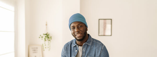 Close-up of a man in a home office with a teal beanie talking about a personal loan through Upstart