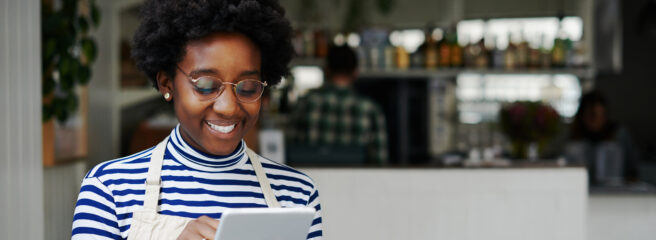 Young woman wearing glasses using an ipad to find places to access money