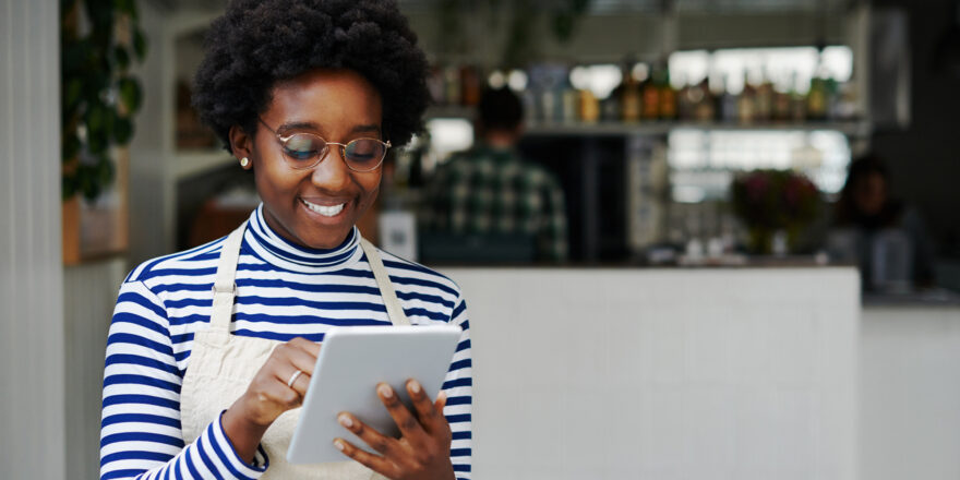 Young woman wearing glasses using an ipad to find places to access money