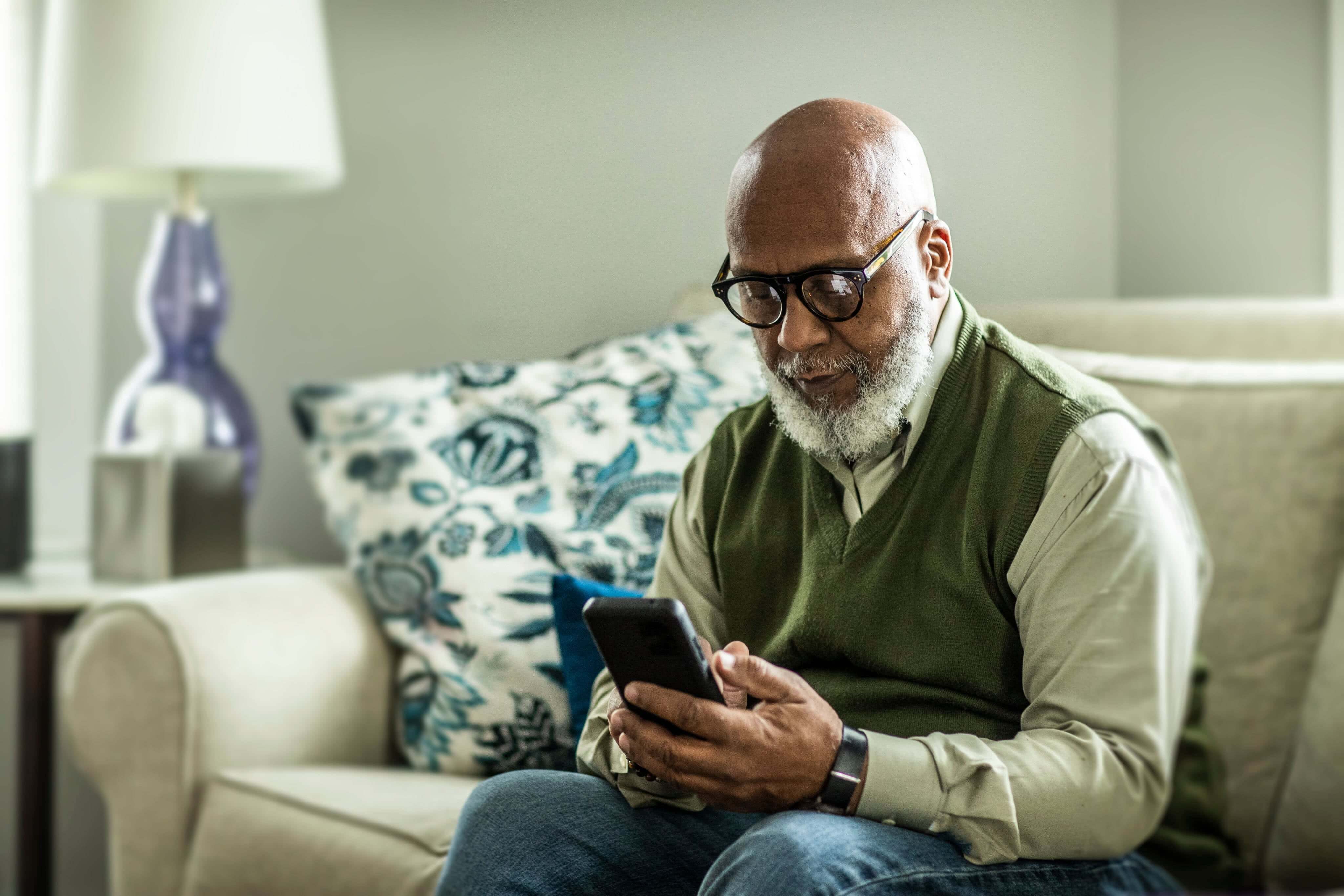 Older man holding a phone and reading about loans for bad credit