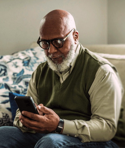 Older man holding a phone and reading about loans for bad credit