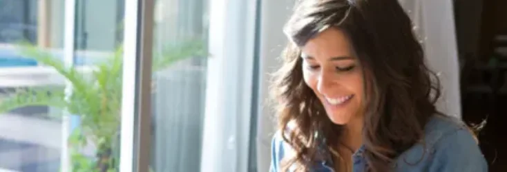 Woman using a tablet smiling - Upstart Personal Loans